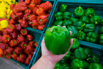 consumerism and people concept - man buying bell peppers or paprika at grocery store