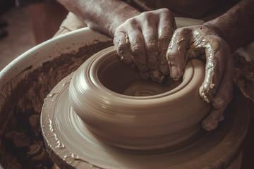 elderly man making pot using pottery wheel in studio. Close-up.