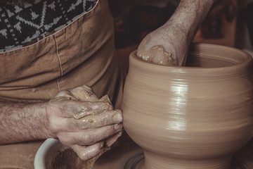 elderly man making pot using pottery wheel in studio