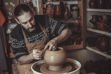 Fototapeta na wymiar elderly man making pot using pottery wheel in studio