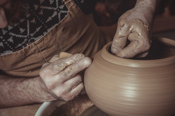 elderly man making pot using pottery wheel in studio
