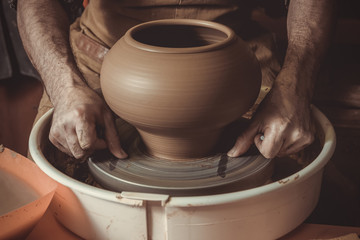 elderly man making pot using pottery wheel in studio