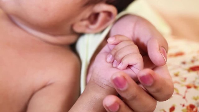 Newborn baby boy gripping mother's finger 