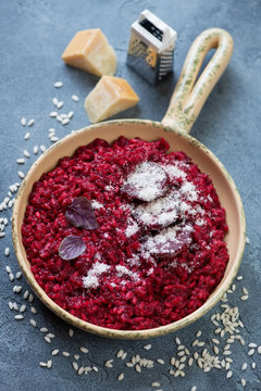 Frying pan with beetroot risotto on a blue stone background, vertical shot