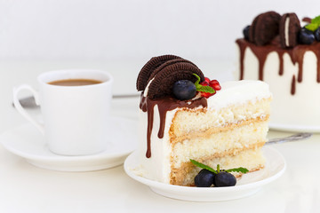 Piece of vanilla layer cake with fresh berries, cream cheese and chocolate biscuits.