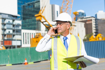 Man architector outdoor at construction area having mobile conversation