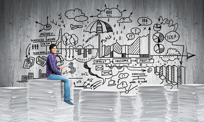 Attractive man sitting on pile of paper documents.