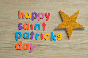 Happy saint Patricks day in colorful letters on a wooden background with a golden star