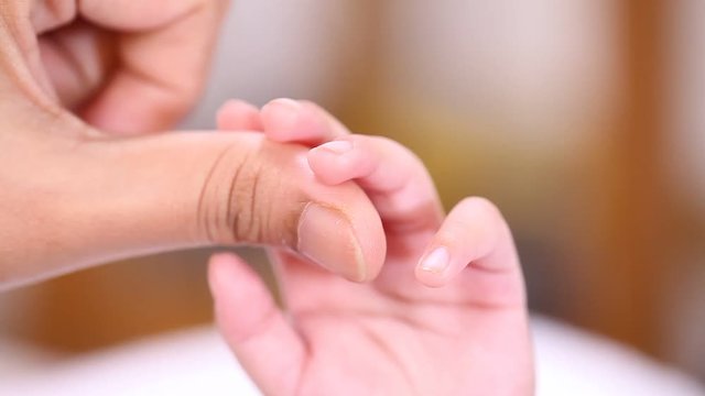 Cute newborn baby boy holding mother's finger 
