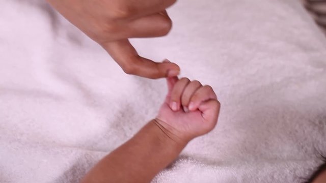 Newborn baby boy gripping mother's finger