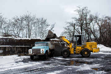 The tractor loads coal into the truck.