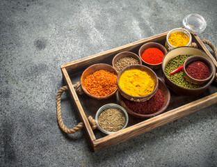 Ground spices in bowls on a wooden tray.