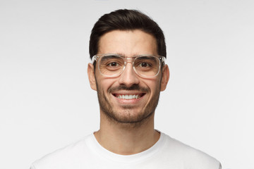 Close up shot of smiling attractive man in white t-shirt and trendy trasparent eyeglasses isolated...