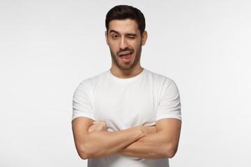 Obraz premium Studio shot of good looking man isolated on grey background looking enterprising and enthusiastic, winking friendly as if inviting to adventure or recommending good benefit