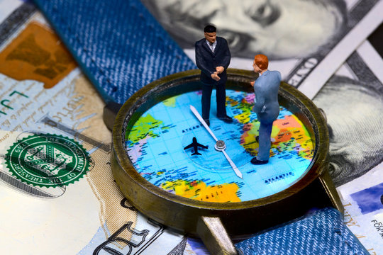 Two businessmen figurines on time and money background. Worldwide business concept.