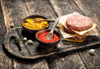 Raw burger with spices and herbs.