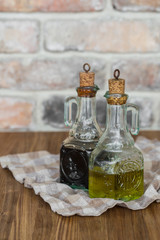 Oil and balsamic vinegar glass bottles with spouts on a napkin on rustic brick wall background with copy space
