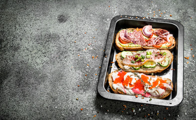 Sandwiches with meat, salami, seafood and fresh vegetables.