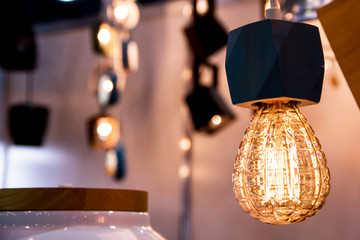 Burning bulb shines weakly on the background blurred yellow romantic lights