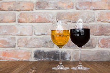 Glasses with red and white wine. Red and white wine glasses on a old brick wall.