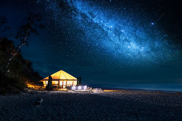 Beach with glowing tent at night with stars