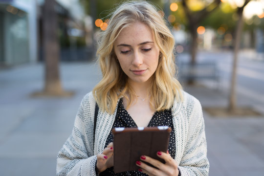 Young caucasian woman walking using tablet computer