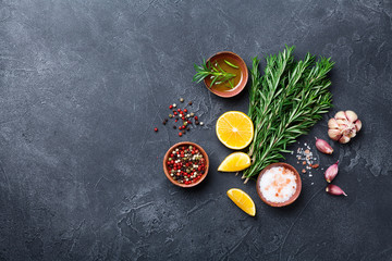 Fresh rosemary and mixed spices on black stone table top view. Ingredients for cooking. Food...