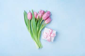 Spring tulip flowers and gift box on blue pastel table top view. Greeting card for Birthday, Womans or Mothers Day. Flat lay.