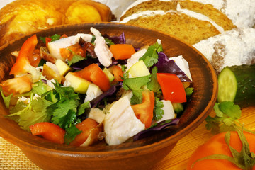 Healthy food. Ceramic bowl with salad with fresh vegetables and chicken. Rural kitchen table.