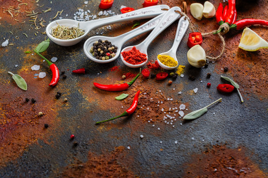 Dry Herbs And Spices In Measuring Spoons On White Stone Kitchen Table