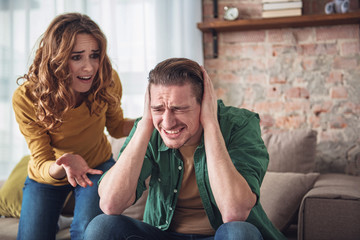 Listen to me. Angry man is closing his ears with desperation while his wife is shouting at him....