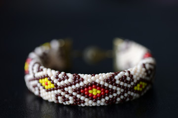 Beige beaded bracelet with oriental pattern on a dark background close up