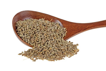 Pile of dried anise seed with wooden spoon on a white background