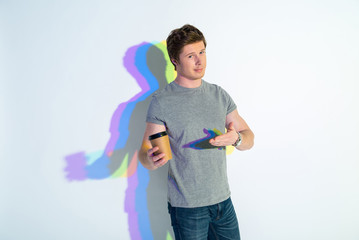 Portrait of happy man standing with colorful shadow pointing at mug of delicious beverage. Rest concept
