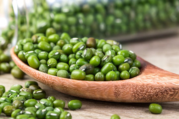 close up green mung beans in wooden spoon on wood plate