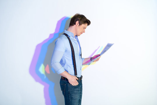 Side view of undistracted man looking through newspaper. Painted reflection reflecting on wall. Publication concept