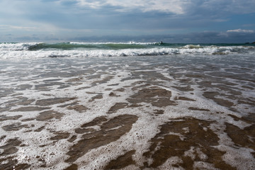 Foamy atlantic ocean wave on beach sand.
