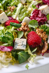 Green salad with blue cheese , raspberry and nuts.