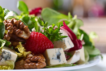 Green salad with blue cheese , raspberry and nuts.