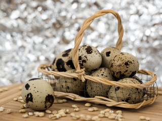 Quail eggs in wicker basket and grains of barley on wooden table