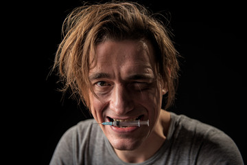 Portrait of happy junked up man with empty squirt in mouth looking at camera. Isolated on background