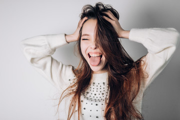 Naklejka premium Funny cheerful woman shows tongue with eyes closed, shouting, fooling around, making a grimace. Positive emotions.