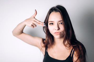 Portrait of emotional girl. Young beautiful woman doing gun gesture on white background