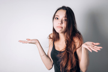 Closeup portrait puzzled clueless young woman with arms out asking what is problem who cares so what I don't know