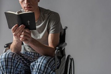 Spirituality concept. Calm disabled man reading bible. Copy space in right side. Isolated on background