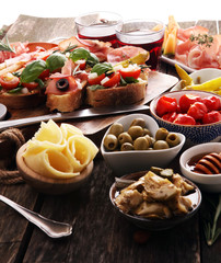 Italian antipasti wine snacks set. Cheese variety, Mediterranean olives, pickles, Prosciutto di Parma, tomatoes, artichokes and wine in glasses