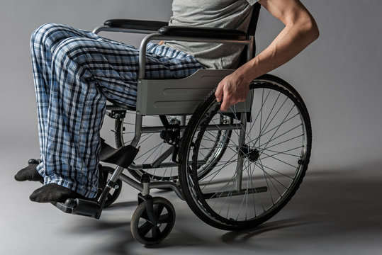 Close up of paralyzed lower half of the man body confined to a wheelchair. Illness concept