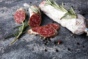 sliced salami and salami sausage on grey background