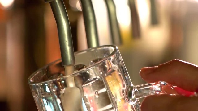 Close up empty glass of beer filling. Beer tap filling empty glass of beer, slow-mo.