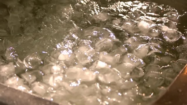 Container with weater filling with ice cubes. Close up pile of ice cubes in water.